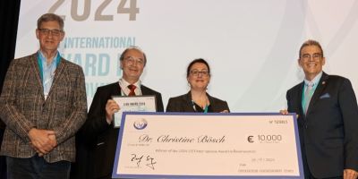 Christine Bosh being handed a huge cheque for 10,000 Euros. She's standing next to three people on the stage.