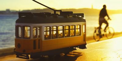 Miniature yellow tram and a person cycling in the background
