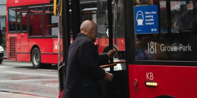 A man stepping into a red bus.