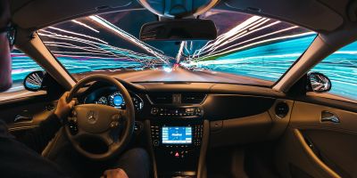 A view of the front windscreen of a car from the inside. The outside is a long exposure shot, so the headlights from the road outside go all down the side of the car.