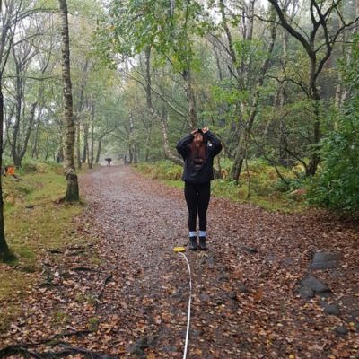 Image of fourth-year Geography BSc student Elinor Sullivan in a forest conducting an experiment.